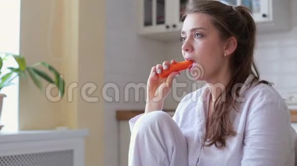 年轻漂亮的女人在客厅里坐在家里吃胡萝卜牙齿疼得厉害视频的预览图
