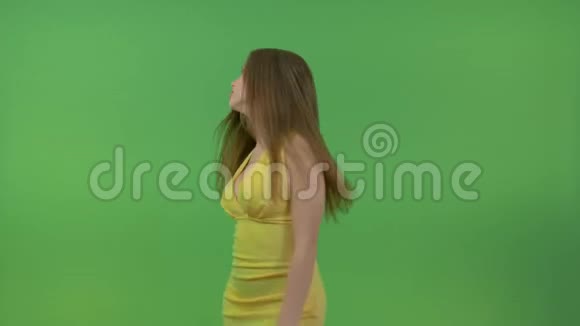 美丽的女孩穿着黄色的裙子在绿色的屏幕上她转过身用手做了个手势视频的预览图
