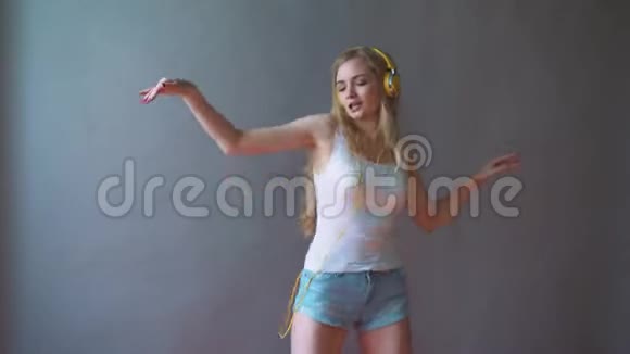 灰色背景的年轻美女听着耳机里的音乐跳舞视频的预览图