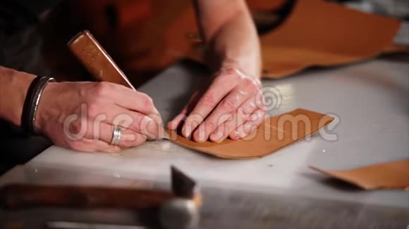 一个男人的手特写镜头他用刀子在皮革细节上做纸条视频的预览图