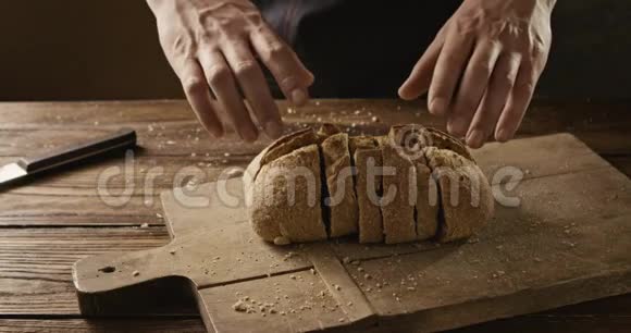 一个穿着黑色围裙的人把切片的新鲜面包放在木板上视频的预览图
