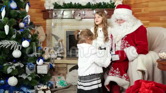 小女孩在他的住所拜访圣诞老人幸福的姐姐坐在圣诞老人的腿上圣诞礼物视频的预览图