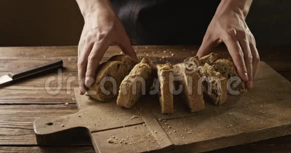 面包师在一张旧的木桌上把新鲜的面包折叠在一块砧板上视频的预览图