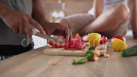 当他的白种人女友坐在的时候他的手在切蔬菜准备食物的特写镜头视频的预览图