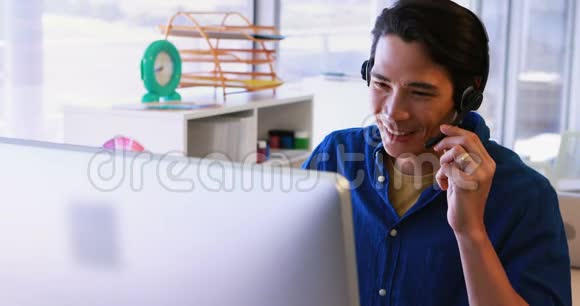 男士头戴式耳机办公桌旁用电脑工作视频的预览图