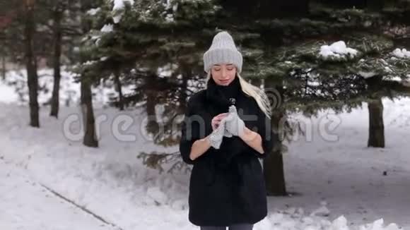 穿黑色毛皮外套的女孩戴上针织手套视频的预览图