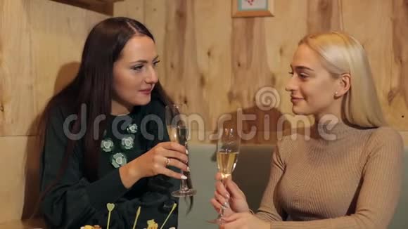两个笑的女孩坐在咖啡馆里喝香槟视频的预览图