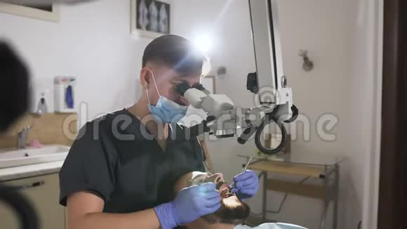 牙科医生在现代牙科办公室使用牙科显微镜进行手术带牙具的男性牙医视频的预览图