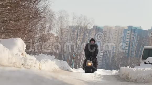 穿着冬装的人骑着带拖车的迷你雪车还有一名乘客在冬季的道路上视频的预览图