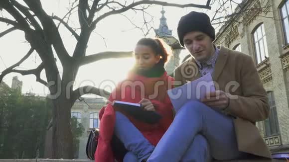 两个学生坐在公园的长椅上写笔记视频的预览图