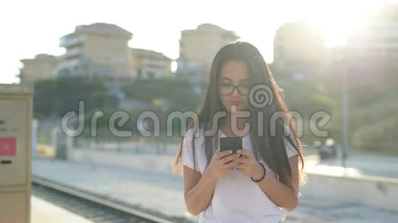 年轻快乐的亚洲旅游妇女在火车站等候电话视频的预览图