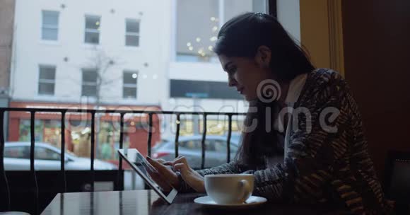 带着平板电脑坐在咖啡馆里的年轻女人动作缓慢拍摄红色电影视频的预览图