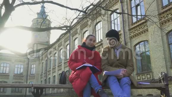 两个准备考试的朋友坐在大学附近公园的长凳上视频的预览图