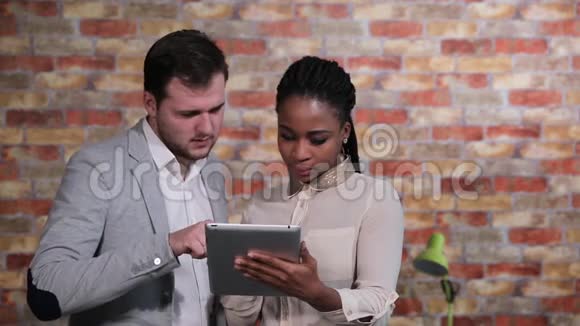商人与正在看平板电脑的美国女商人交谈视频的预览图