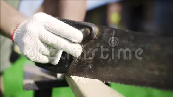 男人在户外用生锈的手锯锯起木棒用木头做DIY作品用木棒切割在那里手工制作视频的预览图