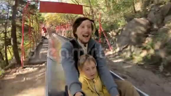 一对父子在秋林中乘坐高山过山车的慢镜头视频的预览图