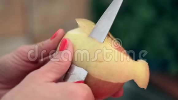 女人的手在用刀子剥红苹果的皮视频的预览图