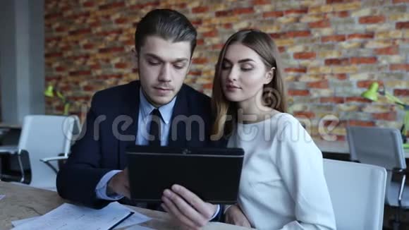 商人和在平板电脑上寻找的女商人交谈视频的预览图