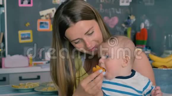 年轻的母亲用杏子喂小儿子视频的预览图
