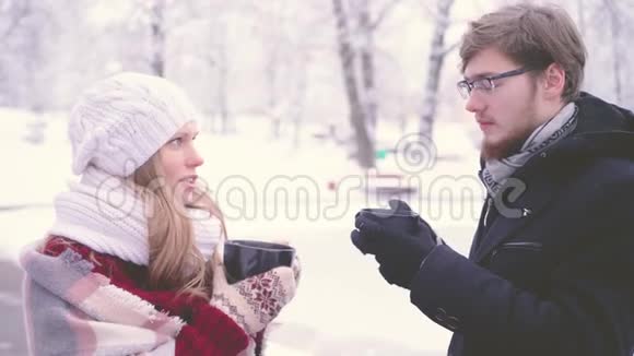 冬天美丽的女孩和长胡子的男人在说着开心的笑着喝着杯子里的热可可视频的预览图