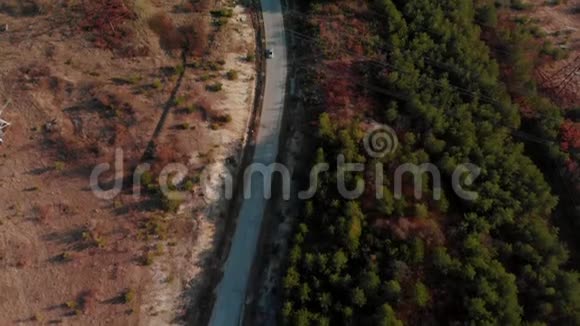 在乡村道路上驾驶汽车的鸟瞰图电影色调无人驾驶飞机飞过电线和沥青路面视频的预览图