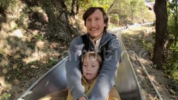 一对父子在秋林中乘坐高山过山车的慢镜头视频的预览图