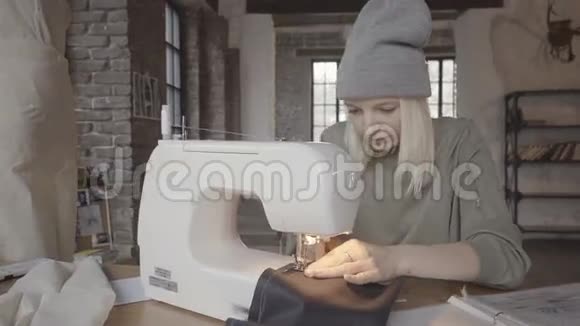 年轻的设计师坐在她的时装工作室前缝纫机和工作的新收藏小生意视频的预览图