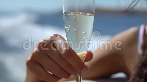 年轻的女人拿着一杯香槟美丽的晒黑的女人手和一杯精致的饮料近距离缓慢缓慢的动作一个视频的预览图