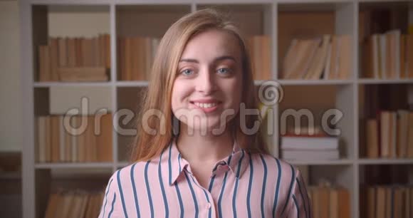 在大学图书馆里年轻漂亮的白种人女学生看着镜头开心地笑着的特写镜头视频的预览图