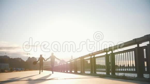 幸福相爱的一对夫妻在河边的城市公园里年轻的男人和漂亮的女人在日落时奔跑慢镜头视频的预览图