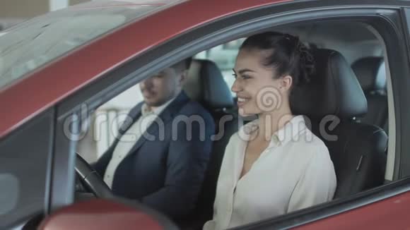 漂亮的女商人从汽车陈列室的推销员那里得到了新车的钥匙视频的预览图