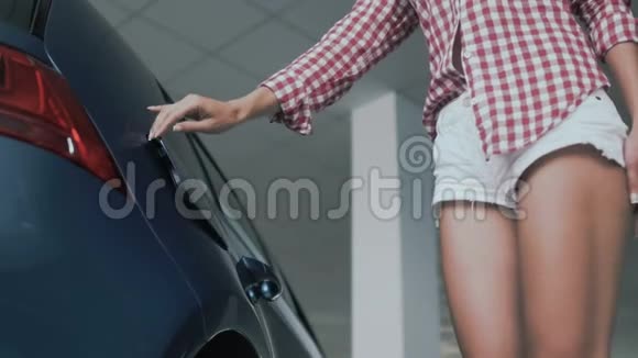 有着苗条黝黑的腿的女人把充电放在电动汽车的电源插座上视频的预览图