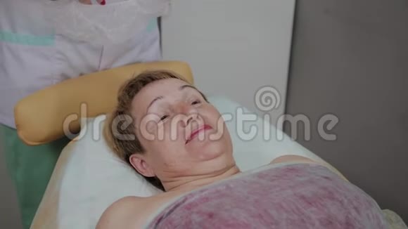一位老年妇女躺在美容诊所的沙发上视频的预览图