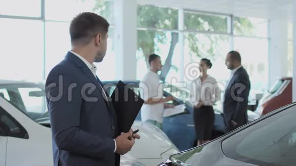 经理照看年轻夫妇在汽车经销店买新车视频的预览图
