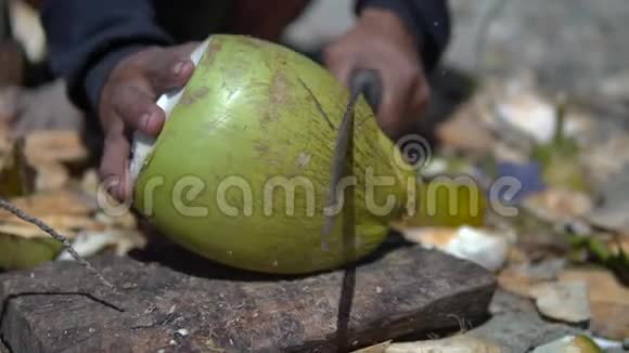当男人用大砍刀切下一个年轻的椰子时伊斯勒曼会慢慢地向我们展示如何获得美味的果汁视频的预览图