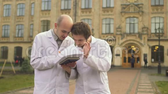 两个穿浴袍的医学生在校园里讨论一些事情视频的预览图