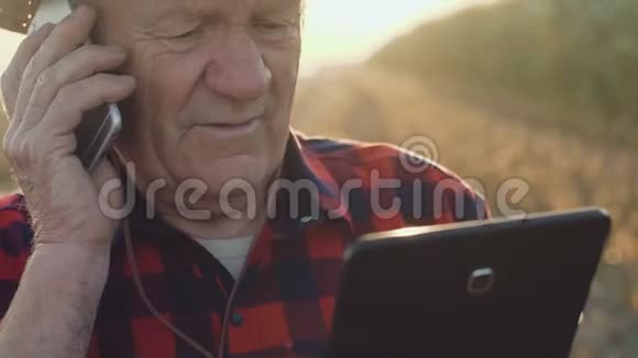 快乐的老农在电话上讲话在田里用平板电脑视频的预览图
