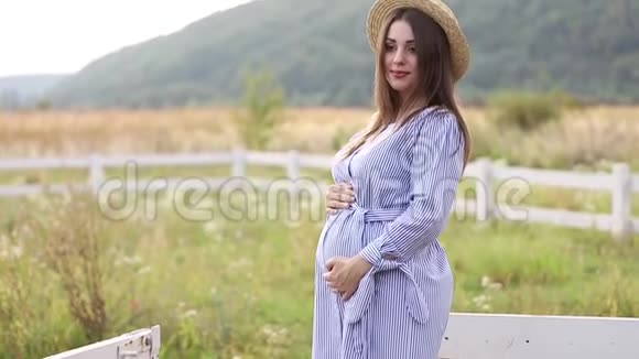 穿着蓝色连衣裙和针织帽子的孕妇拍照视频的预览图