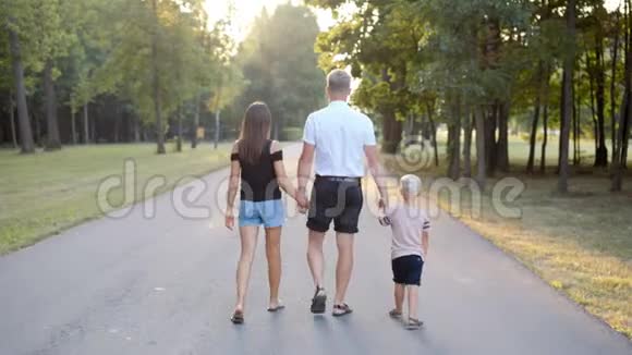 幸福的年轻家庭走在公园里牵着小儿子的手视频的预览图
