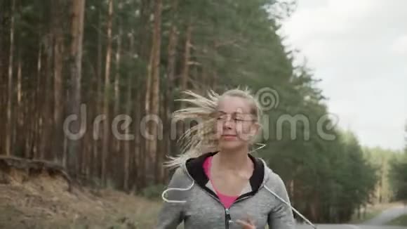 女运动员沿着松树沿着乡村道路奔跑慢动作视频的预览图