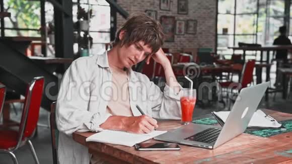 年轻漂亮的穿着轻便衣服的年轻人在沉思中把自己的想法写在笔记本上视频的预览图