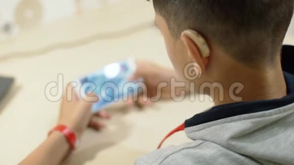 一个听力障碍的年轻人在智能手机上玩助听器视频的预览图
