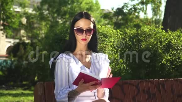 戴墨镜的美女在公园看书视频的预览图