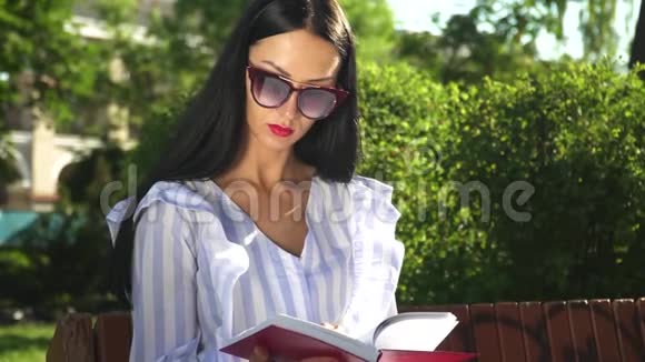 夏天公园里戴太阳镜穿脱上衣的时髦女人看书视频的预览图