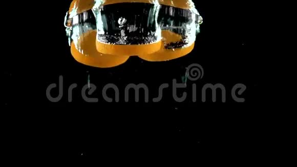 三片橙片在黑色背景下溅入水中视频的预览图
