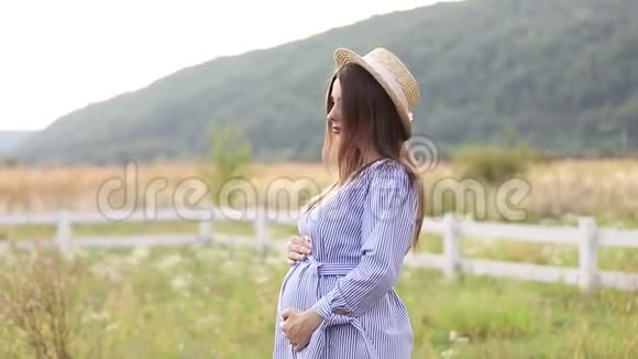 穿着蓝色连衣裙和针织帽子的孕妇拍照视频的预览图