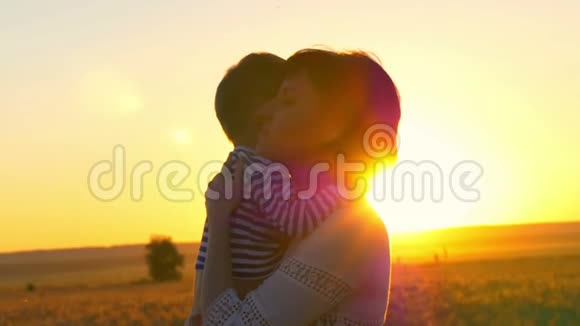 快乐的母亲在夕阳的映衬下抱着孩子在麦田里视频的预览图