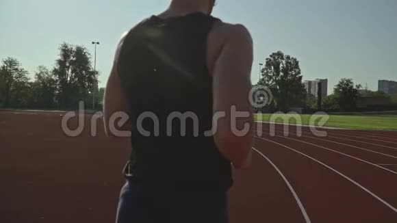 从后面看作为一个运动员在阳光明媚的日子沿着跑道跑慢动作射击泄漏耀斑视频的预览图
