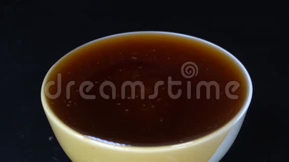在白碗里浇蜂蜜特写蜂蜜在黑色背景下宏视频的预览图