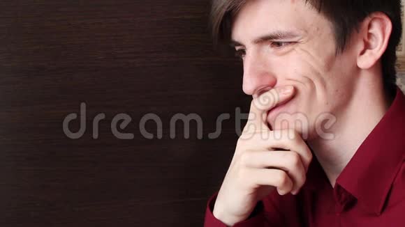 一个穿红色衬衫的年轻人手指在嘴唇上仔细看着视频的预览图
